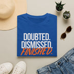Blue t-shirt with 'Doubted. Dismissed. Finished.' text, surrounded by casual items on a light surface.