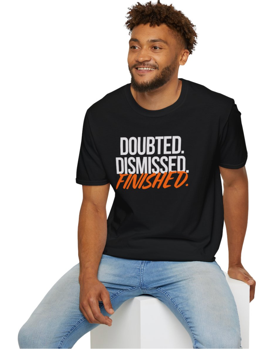Man wearing a black t-shirt with motivational text, sitting on a white stool against a white background